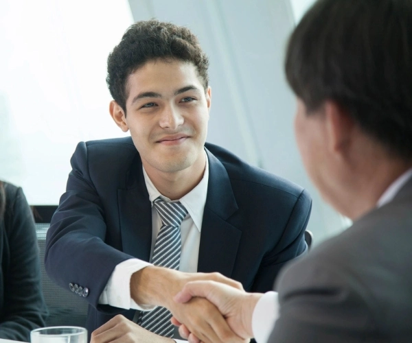 A man in suit shaking hands with another person.